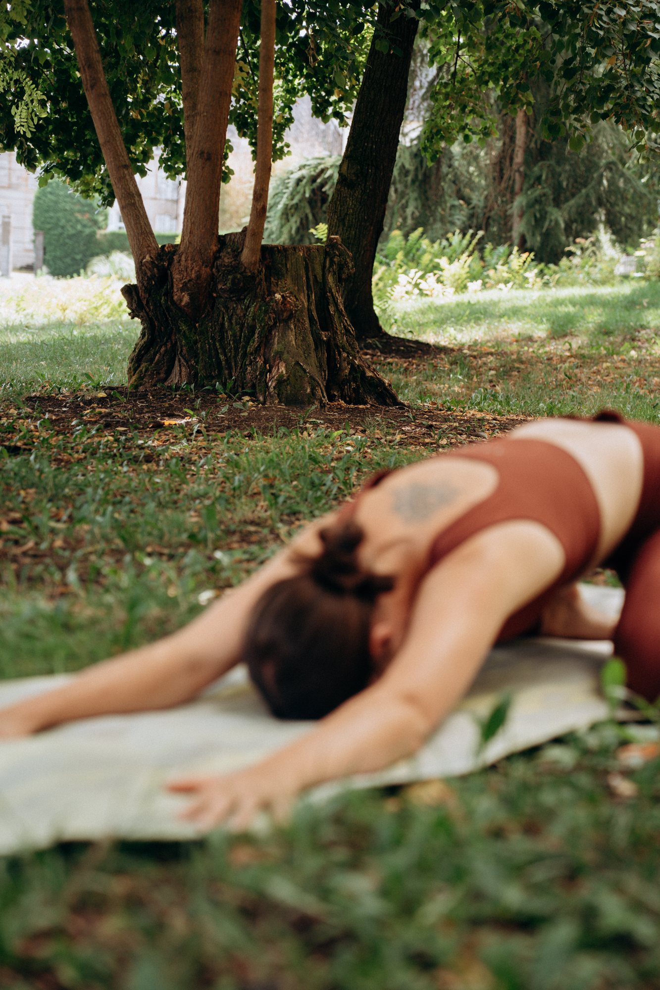 Posture de l'enfant sur un tapis dans l'herbe, sous un arbre